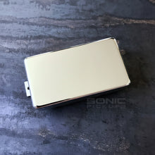 A chrome-finished guitar humbucker pickup on a dark, textured slate surface, with a 'SONIC PICKUPS' watermark overlay.