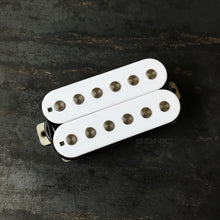Two white guitar humbucker pickups with gold-toned metal springs, displayed on a dark textured background. A 'SONIC PICKUPS' watermark is visible on the right side.